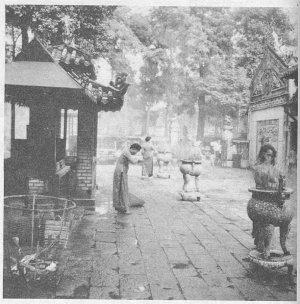 Burning joss sticks and bowing as acts of   veneration in a courtyard for Confucian ancestor worship